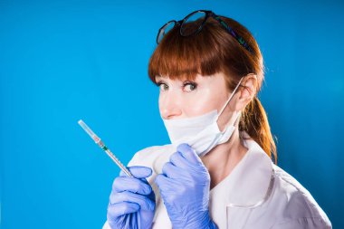 kadın doktor tıbbi maskeli bir şırınga elinde tutan gülümseyerek