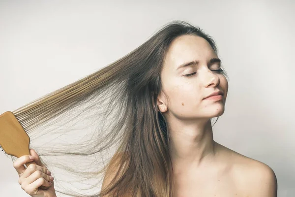 Femme se brossant les cheveux avec plaisir, les yeux fermés, soins de santé — Photo
