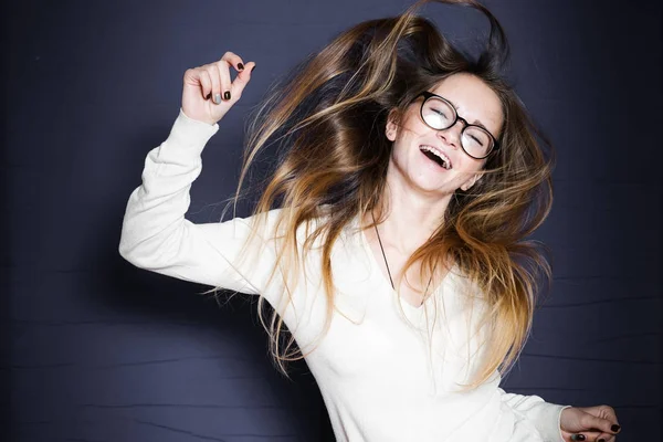 Mädchen mit Brille springt vor Freude auf schwarzem Hintergrund auf — Stockfoto