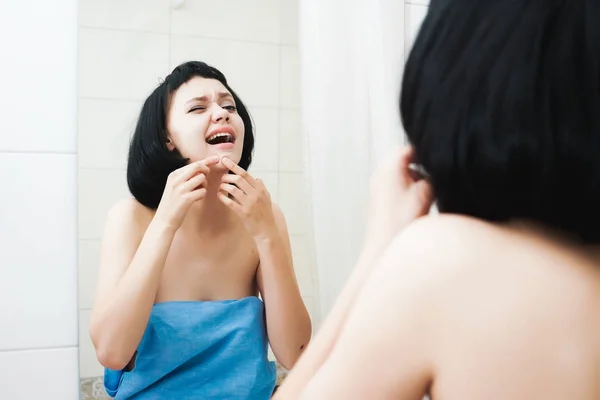 Дівчина з чорним волоссям стискає себе приплив, дивлячись у дзеркало — стокове фото