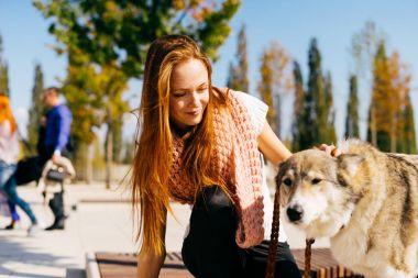 güzel genç Kızıl saçlı kız büyük köpeğini ahşap bir bankta oturan ile parkta yürüyüş