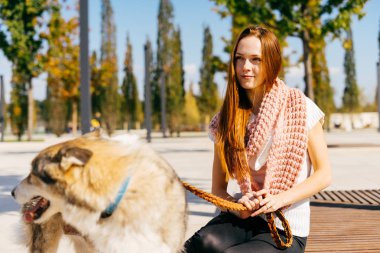 güzel genç Kızıl saçlı kız büyük köpeğini ahşap bir bankta oturan ile parkta yürüyüş