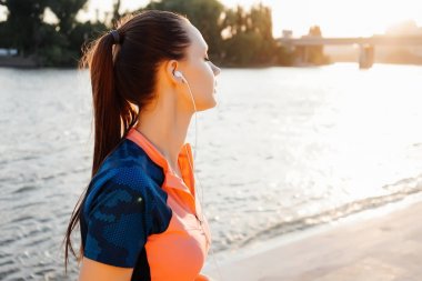 kulaklık kız nehrin kıyısında çalıştırmak bir akşam gerçekleştirir