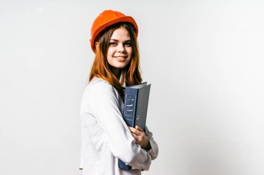 Kız bir portakal inşaat kask içinde bir klasör tutar