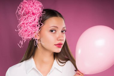 bir kız ciddi bir ifade ile bir pembe hava balonu tutar