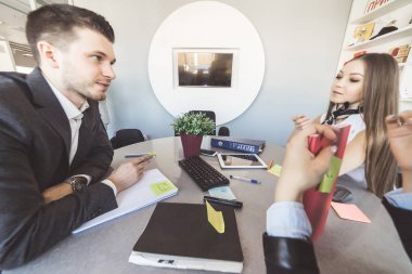ofis takım elbiseli üç genç insanlar aktif olarak masada oturan bir şey görüşüyorlar