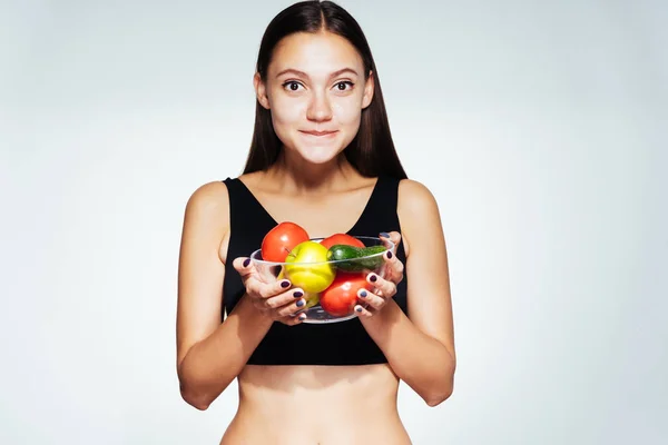 Молодая красивая девушка хочет похудеть, держит тарелку с полезными овощами и фруктами в руках — стоковое фото