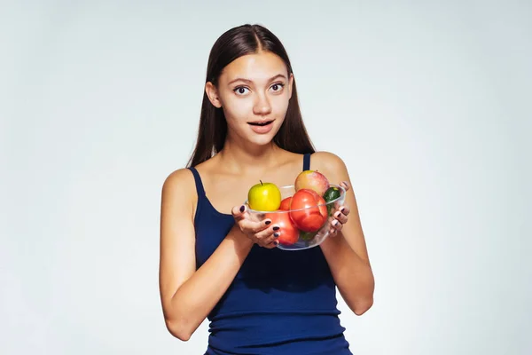 Молодая красивая девушка хочет похудеть, держит тарелку с полезными овощами и фруктами в руках — стоковое фото