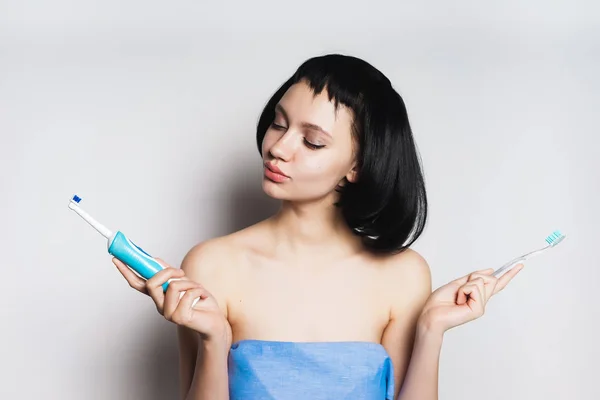 Девушка с черными волосами держит в руках зубные щетки — стоковое фото