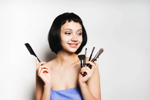 Menina com cabelo preto está segurando um conjunto de escovas — Fotografia de Stock