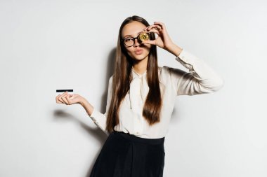 altın bir bitcoin ve bir banka kartı tutan genç başarılı modern iş kadını