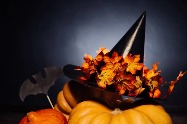 Een compositie voor het versieren van een huis voor halloween leugen gele en oranje pompoenen, een grote zwarte heks hoed — Stockfoto