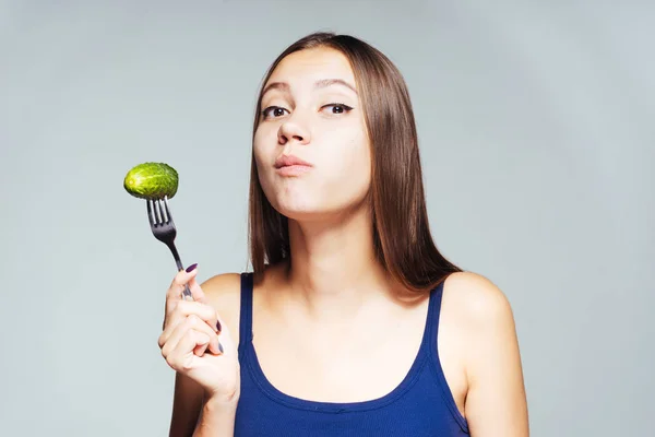 Una joven atlética mira su figura, come un pepino bajo en calorías — Foto de Stock