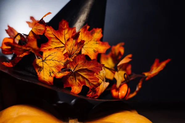 En komposition för att dekorera ett hus för halloween lögn gula och orange pumpor, en stor svart häxa hatt — Stockfoto