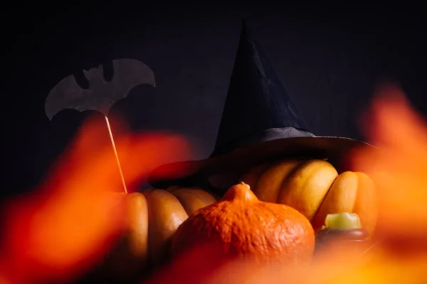 Samenstelling voor het verfraaien van het huis voor halloween liggen gele en oranje kalebassen, branden geurkaarsen en een grote zwarte heks hoed — Stockfoto