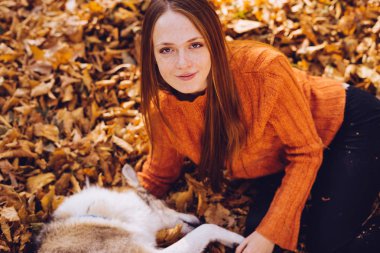 Kızıl saçlı kız büyük köpeğini sonbahar düşmüş bir yığın içinde ile oynarken parkta ile yürüme bırakır