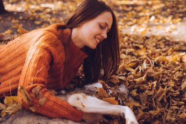 Kızıl saçlı kız büyük köpeğini sonbahar düşmüş bir yığın içinde ile oynarken parkta ile yürüme bırakır
