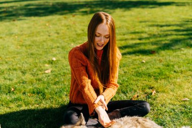 Kızıl saçlı kız büyük köpeğini zümrüt Çimenlikte oturan parkta ile yürüme