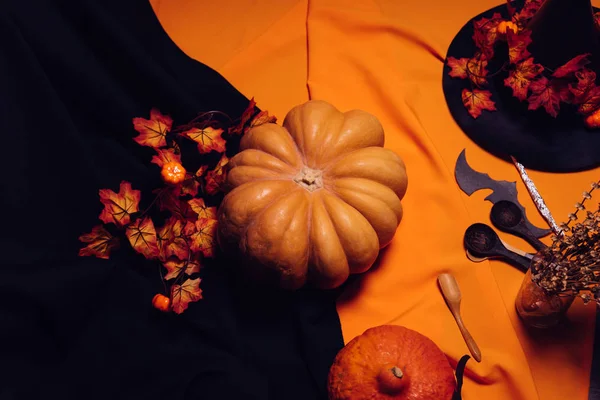 Sammansättning för att dekorera huset för halloween, lögn gula och orange pumpor på varandra, en stor svart häxa hatt dekorerad med gula hösten lämnar, träslevar — Stockfoto