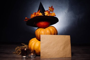 Cadılar Bayramı için bir ev dekorasyon için bir kompozisyon yalan sarı ve turuncu su kabakları, büyük kara cadı şapkası sarı sonbahar ile dekore edilmiş bırakır ve yanan mumlar