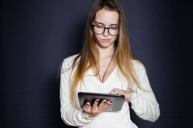 büyük gözlüklü güzel kız mavi bir arka plan üzerinde izole onun tablet ekranında memnun görünüyor