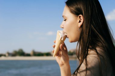 Sevgili Bayan yürüyüşe lezzetli dondurma yemek. Kız nehir arka plan üzerinde