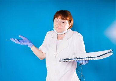 Kızıl saçlı kadın bir beyaz tıbbi soyunma elbise, eldiven ve bir dergi kayıt hastalar için tutan elleri yayılır