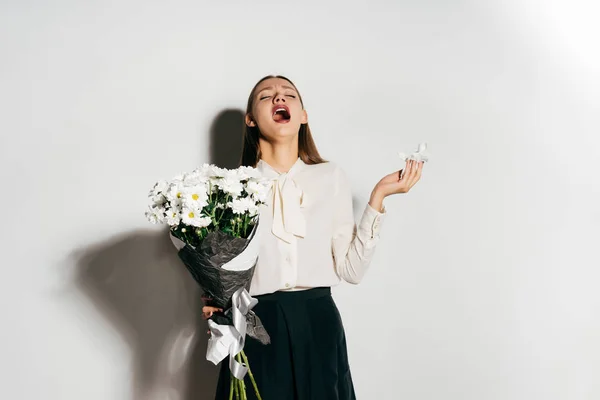 Jovem menina adorável feliz segurando um grande buquê de flores brancas nas mãos e espirros porque ela é alérgica — Fotografia de Stock