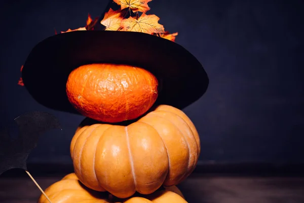 En komposition för att dekorera ett hus för halloween, ligga gula och orange pumpor, en stor svart häxa hatt dekorerad med gula höstlöv — Stockfoto