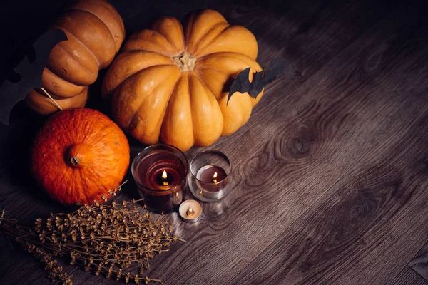 Композиция для украшения дома на Хэллоуин, лежат желтые и оранжевые тыквы, горящие ароматические свечи — стоковое фото