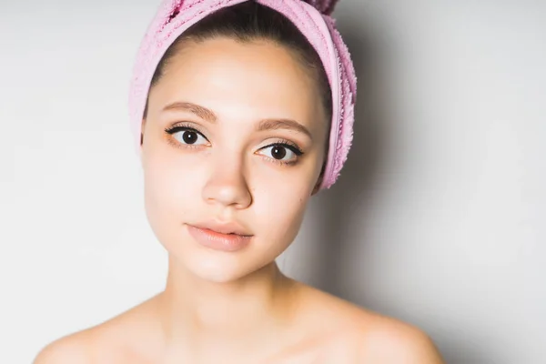 Κορίτσι μετά την ντους με μια ροζ πετσέτα στο κεφάλι της χαριτωμένο εξετάζει τη φωτογραφική μηχανή, που απομονώνονται σε λευκό φόντο — Φωτογραφία Αρχείου