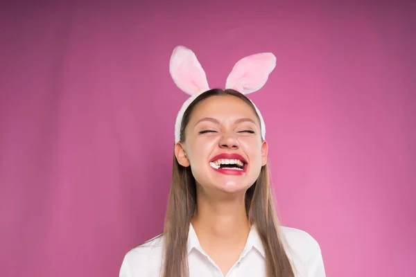 Ragazza con lunghe orecchie sulla testa gomma da masticare e ridere, isolata su uno sfondo rosa — Foto Stock