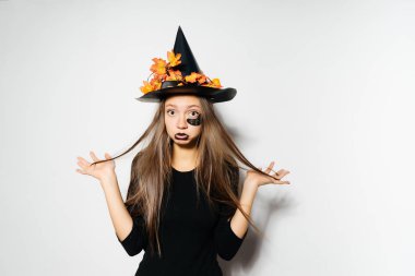 seksi, genç bir Gotik kadın bir cadı, Cadılar Bayramı, sarı yaprakları ile süslenmiş büyük bir siyah şapka şeklinde üzgün görünüyor