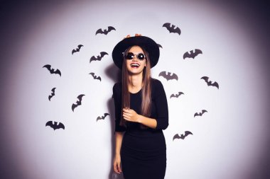 genç seksi Gotik kadın bir cadı, sarı yaprakları ile süslenmiş büyük siyah bir şapka, güneş gözlüğü, gülüyor takıyor Cadılar Bayramı olarak görüntü