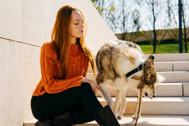 Genç şirin Kızıl saçlı kız ile onun köpek merdiven Beton üzerinde oturan parkta yürüyüş