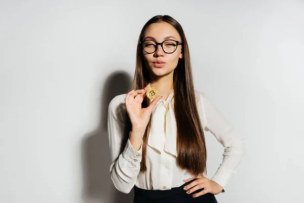 Junge erfolgreiche selbstbewusste Frau mit Brille hält einen Gold-Bitcoin in der Hand — Stockfoto