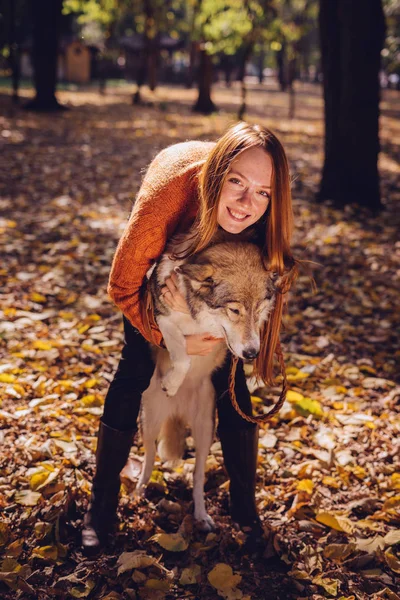 Jovem bonito menina ruiva andando com seu cão no parque, em torno de um monte de folhas caídas no outono — Fotografia de Stock