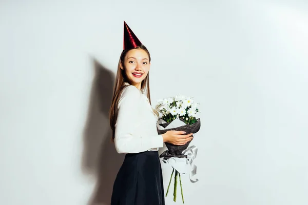 Joven hermosa chica celebra algo, en una gorra roja, sosteniendo un gran ramo de flores blancas — Foto de Stock