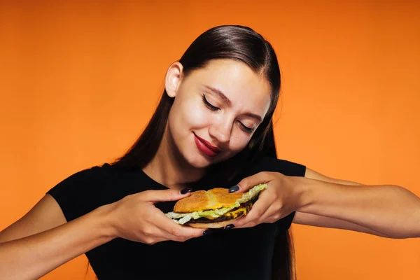 Jovem menina bonita quer perder peso, detém um hambúrguer calórico prejudicial — Fotografia de Stock