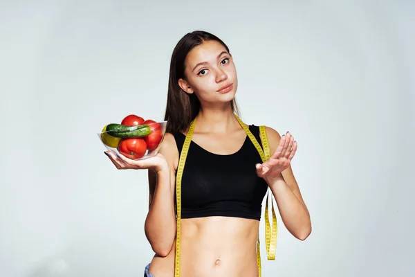 Ένα νεαρό κορίτσι αθλητικά ρολόγια το σχήμα της, κατέχει μια πλάκα με την χρήσιμη λαχανικά και φρούτα στα χέρια της — Φωτογραφία Αρχείου