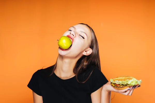 Mladá krásná dívka se chce zhubnout, jí zdravé jablko místo škodlivé vysokokalorickou burger — Stock fotografie