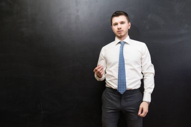 bir kravat ile beyaz bir gömlek bir sevimli adam büyük Kurulu tarafından duruyor ve kameraya bakıyor