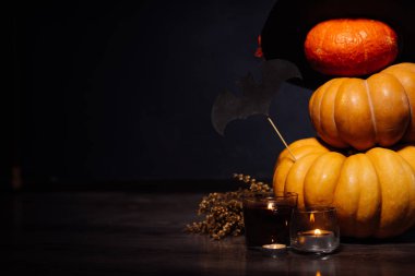 Cadılar Bayramı için bir ev dekorasyon için bir kompozisyon yalan sarı ve turuncu mumlar, bir mum yanıyor, büyük kara cadı şapkası