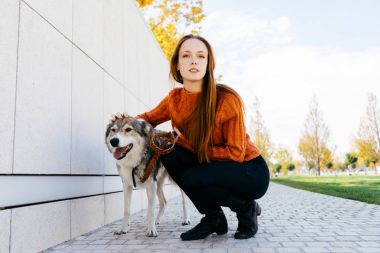 genç güzel kızıl saçlı kız beyaz duvara yakın poz ile parkta, onun köpek yürüyor