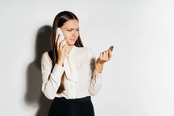 Jovem sexy bem sucedido menina falando no telefone, segurando um bitcoin dourado e olhando descontente — Fotografia de Stock