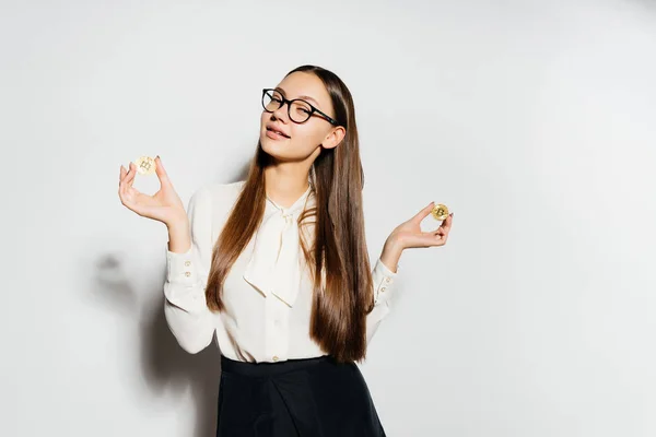 Jovem sexy bem sucedido menina em óculos detém bitcoins dourados em mãos — Fotografia de Stock