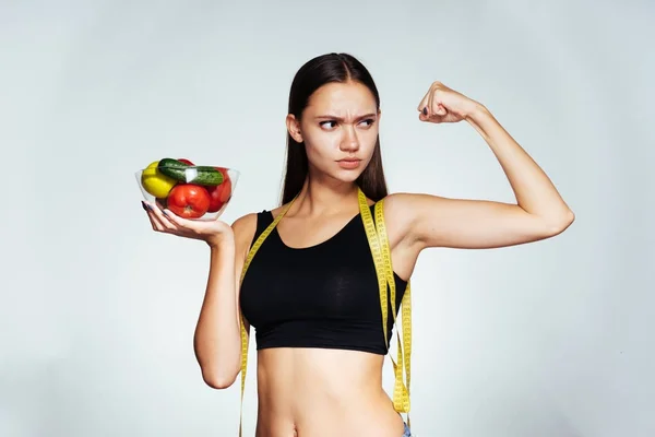 Mladé krásné sportovní dívka sleduje její postavu, drží desku s nízkokalorickou zeleninu a ovoce ve svých rukou — Stock fotografie