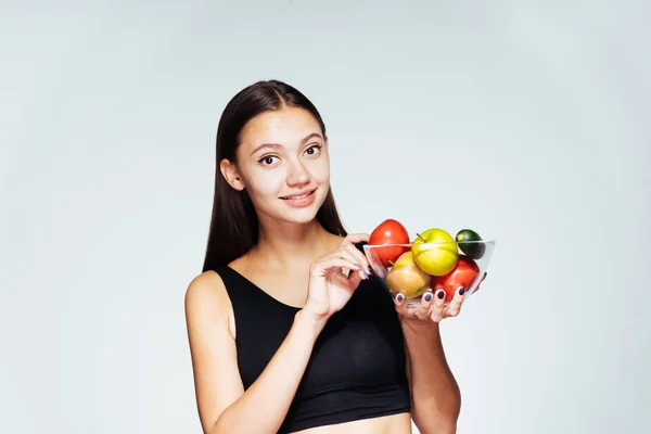 Mladé krásné sportovní dívka sleduje její postavu, drží desku s nízkokalorickou zeleninu a ovoce ve svých rukou — Stock fotografie