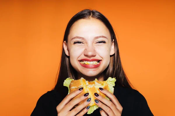 Молодая счастливая девушка хочет похудеть, но ест калорийный вредный бургер — стоковое фото