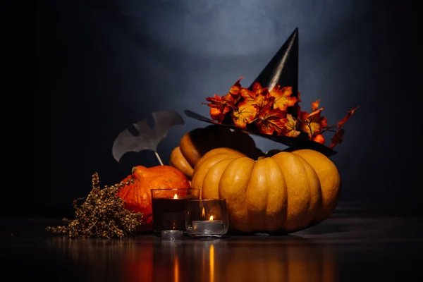 En komposition för att dekorera ett hus för halloween, ligga gula och orange pumpor, brinnande doftljus, en stor svart häxa hatt — Stockfoto